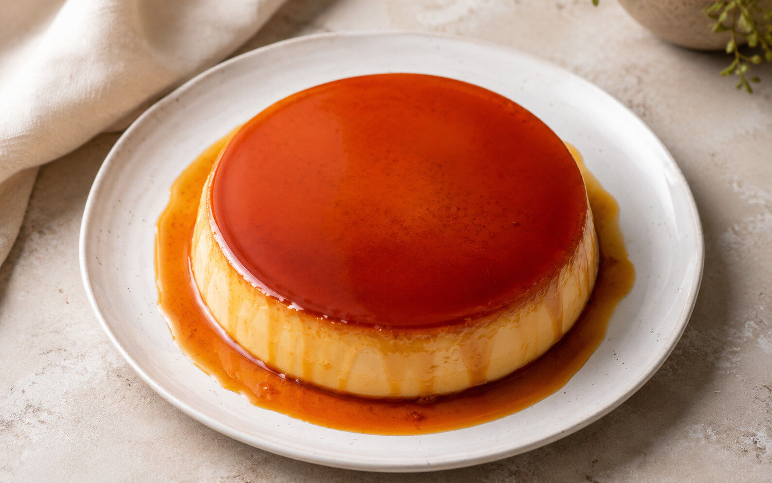 A whole flan unmolded onto a plate with caramel sauce pooling around the base