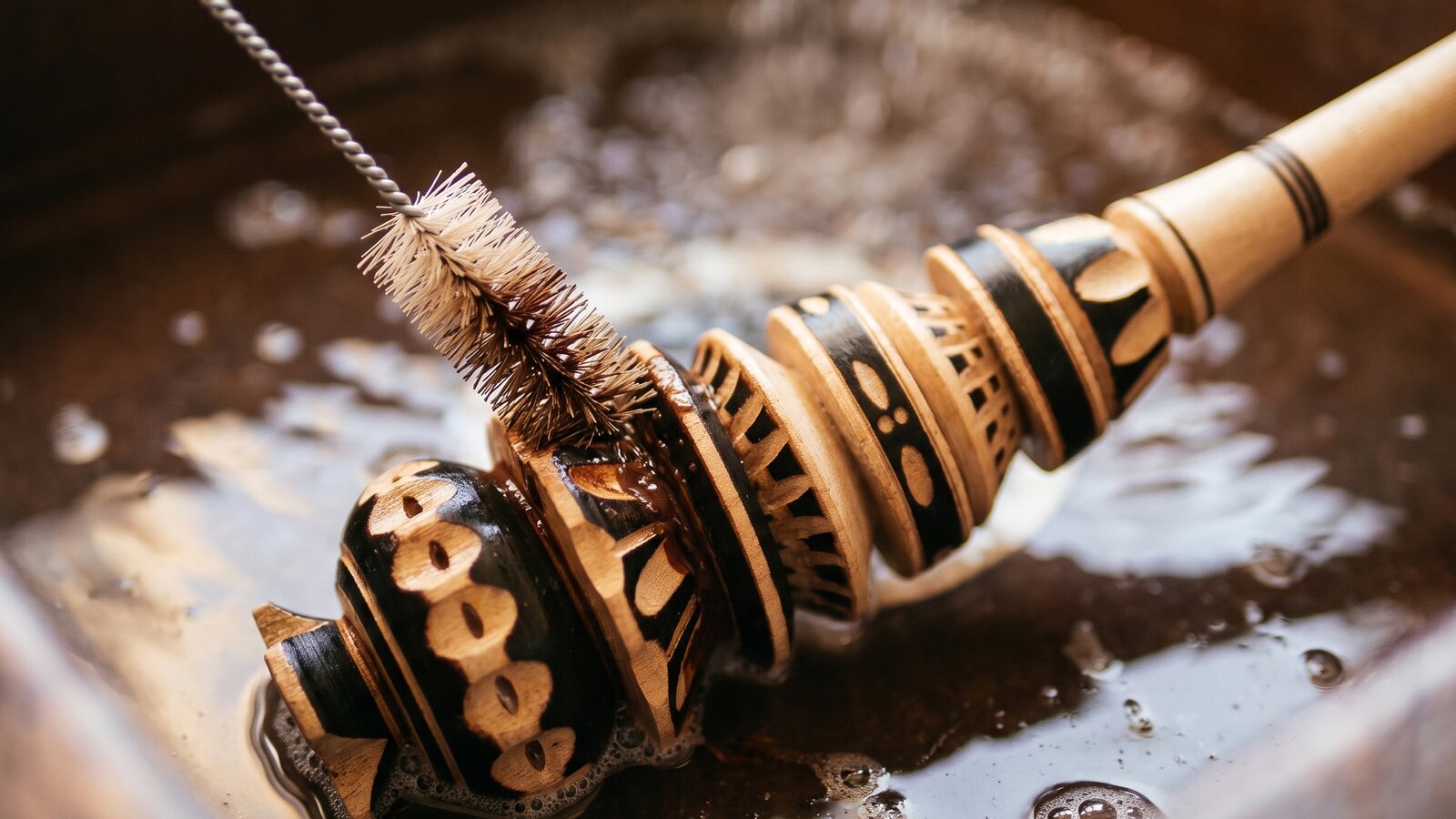 A small brush cleaning residue out of a molinillo's carved rings